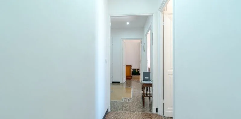 A bright hallway with open doorways and a tiled floor.