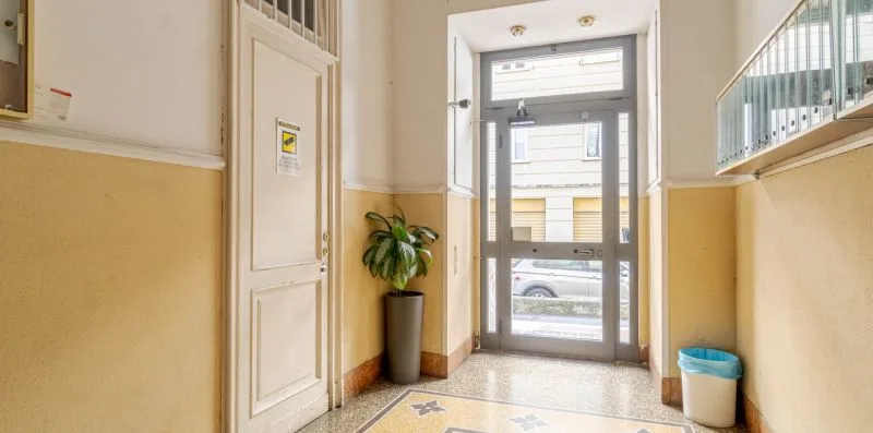A building entrance lobby with a glass door and a potted plant.