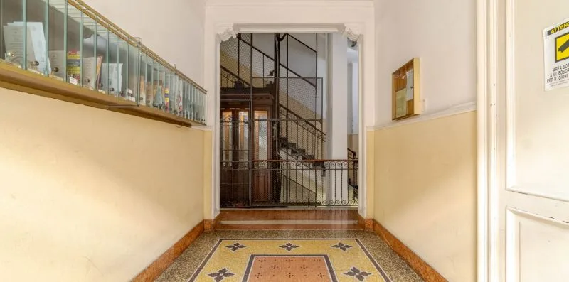 A tiled hallway leads to a stairwell behind a metal gate.