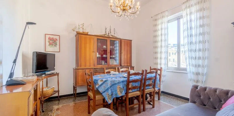 A dining area with a wooden table, chairs, and a cabinet beside a bright window.