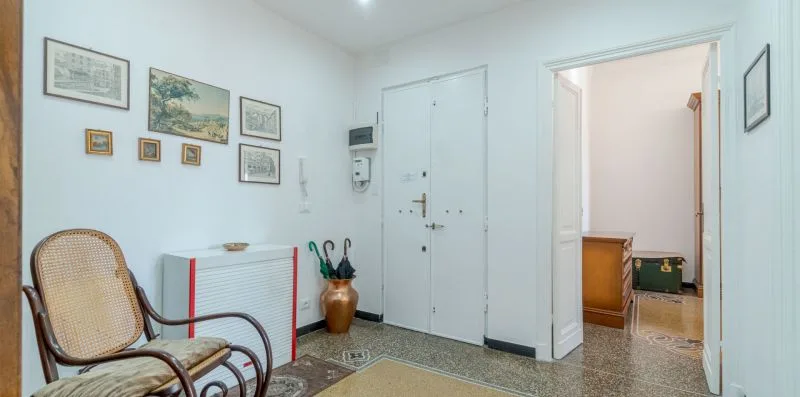 A bright entry hall with framed pictures, a white door, and seating.