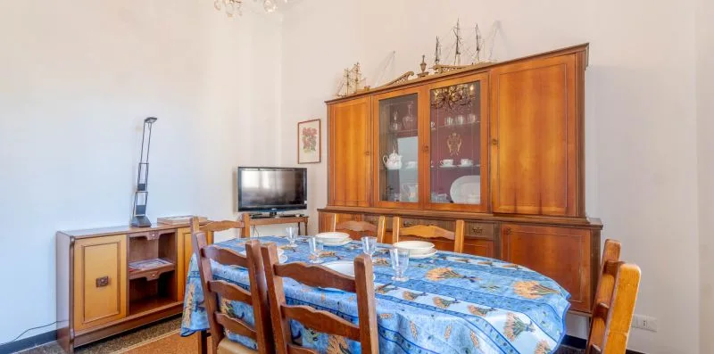 A dining room with a blue-covered table and wooden chairs.
