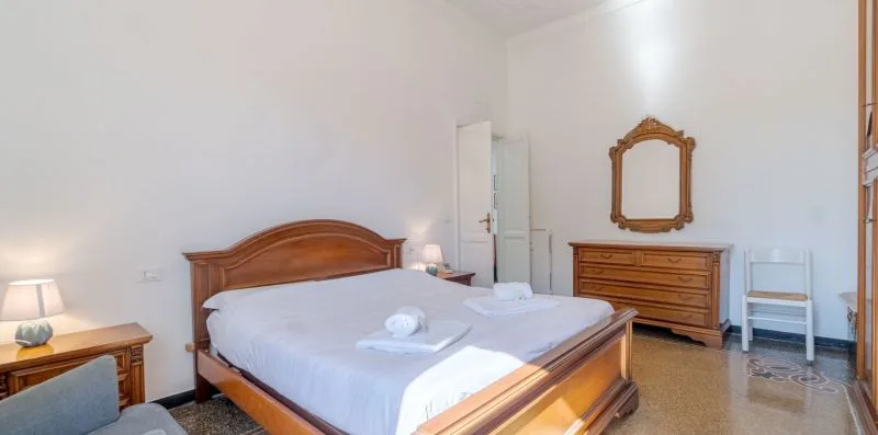 Dormitorio con una cama de madera, una cómoda y toallas dobladas sobre la cama.
