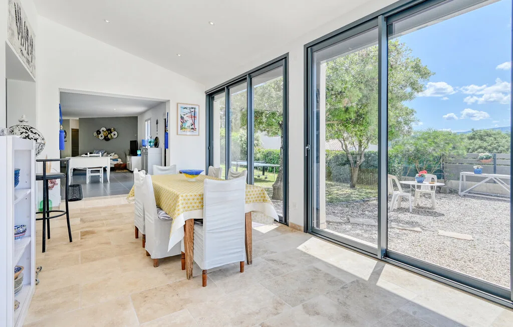 A bright dining area with a table beside large glass doors opening onto a patio.