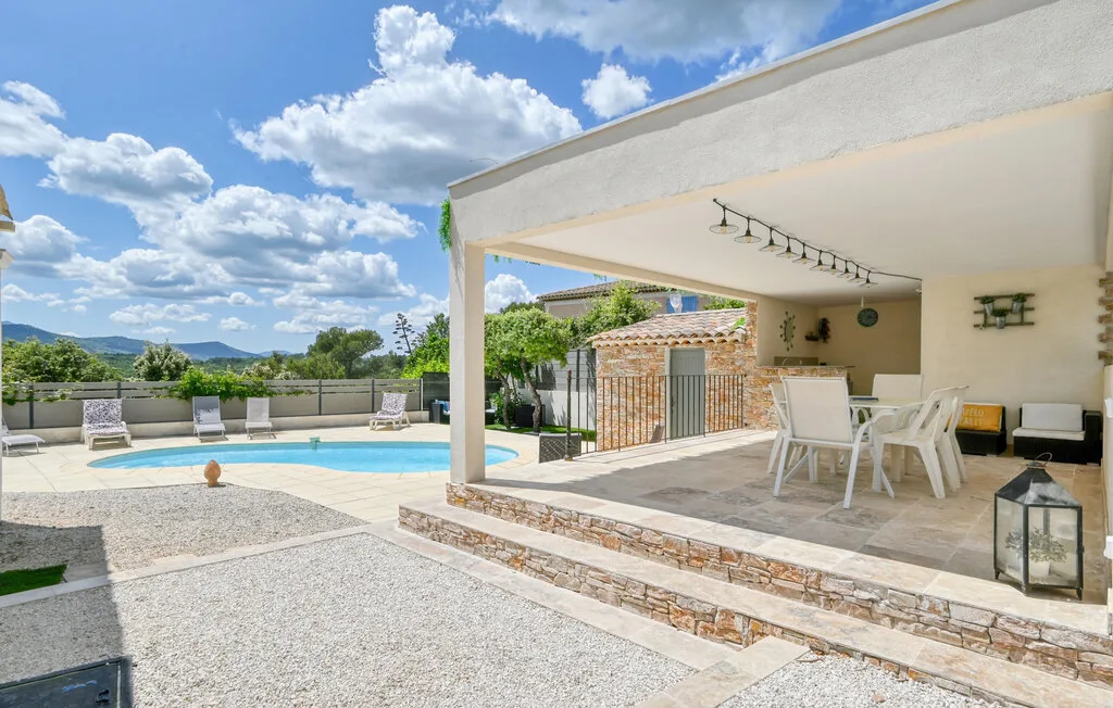 Outdoor patio with a dining table beside a swimming pool.