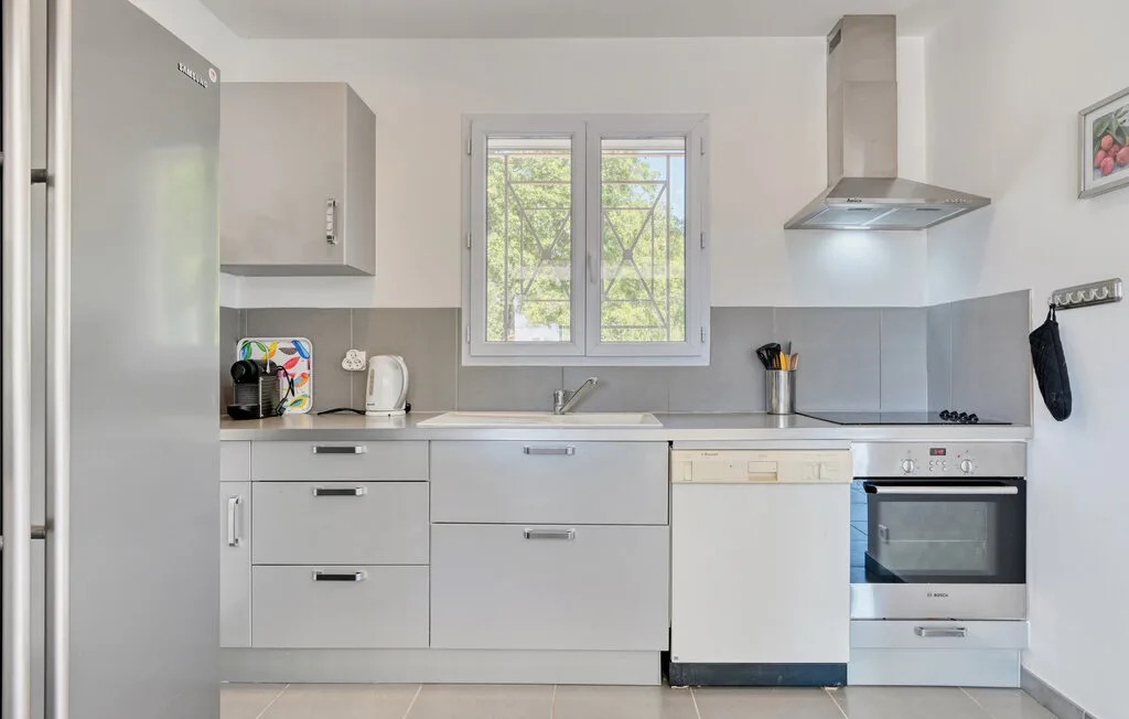 A bright kitchen with gray cabinets, a countertop, and a window.