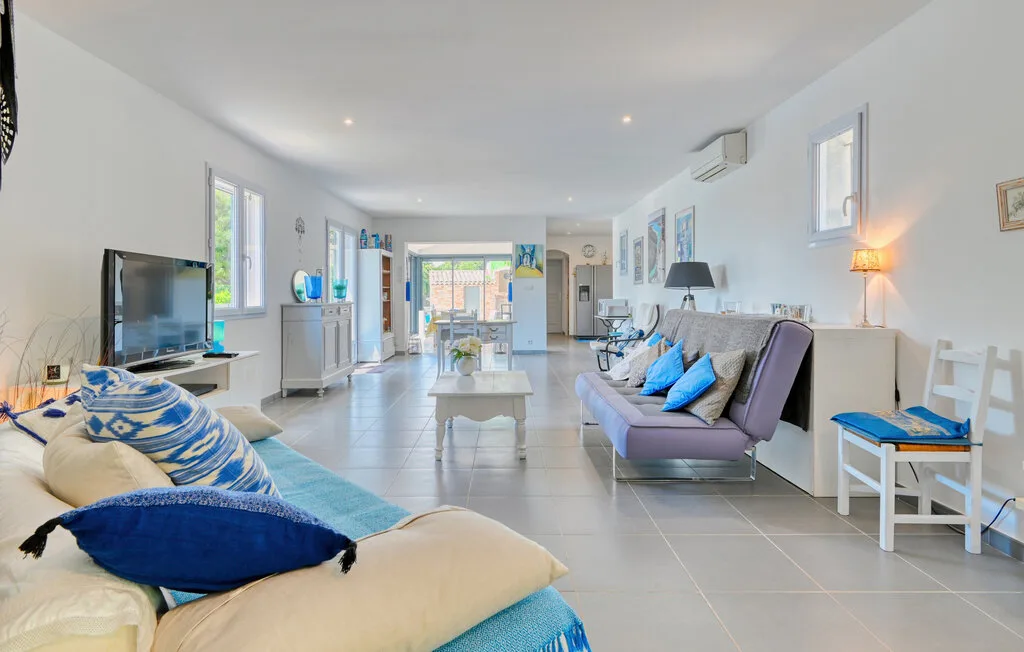 A bright living room with seating, a television, and glass doors to the outside.