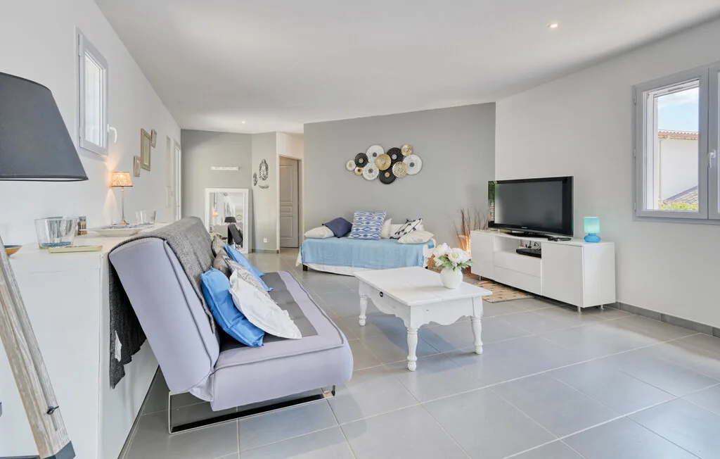 A bright living room with seating, a coffee table, and a television.