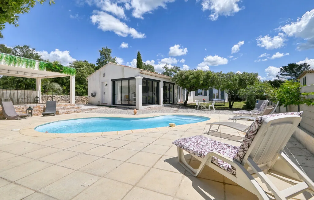 An outdoor swimming pool and paved patio sit beside a modern building.