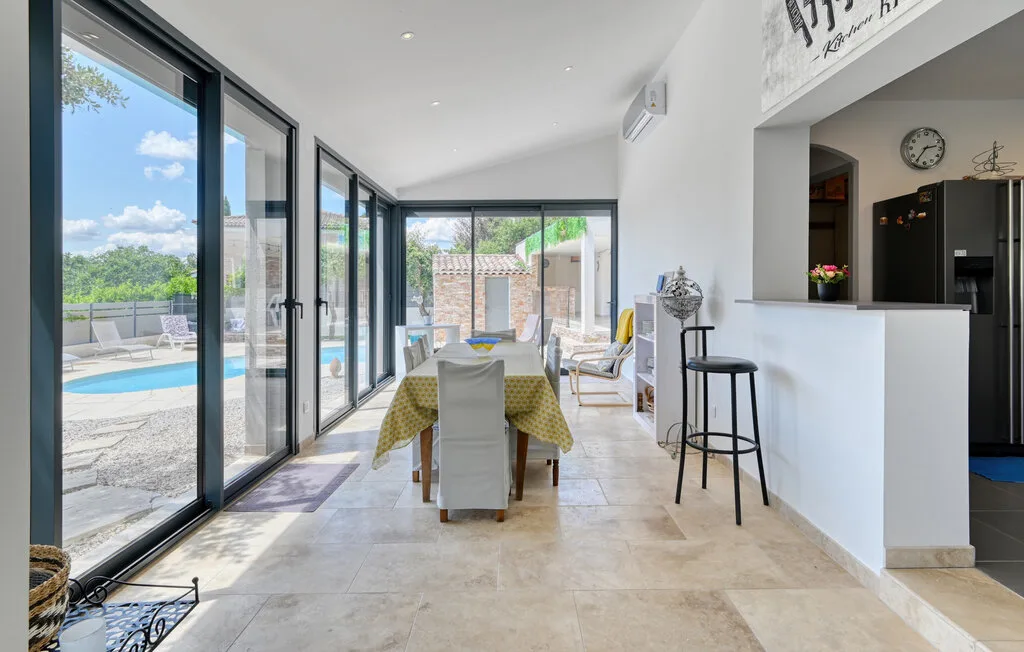 A bright dining area opens onto a patio and pool through large windows.