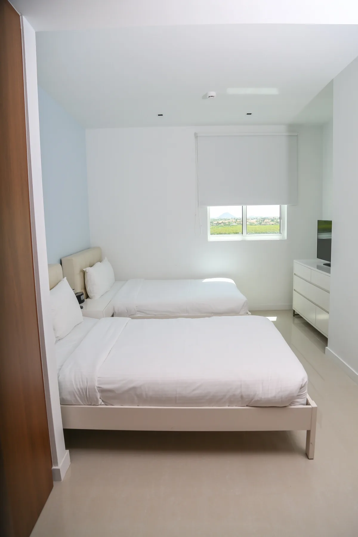 Sink into crisp, clean linens in your bright bedroom with two cozy beds, modern furnishings, and a window framing peaceful views.