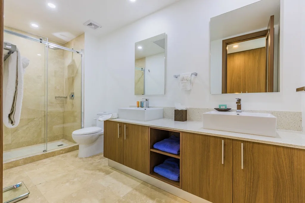 Refresh in your sleek dual-sink bathroom with a spacious walk-in shower, modern cabinetry, and plush towels—everything you need for a comfortable stay.