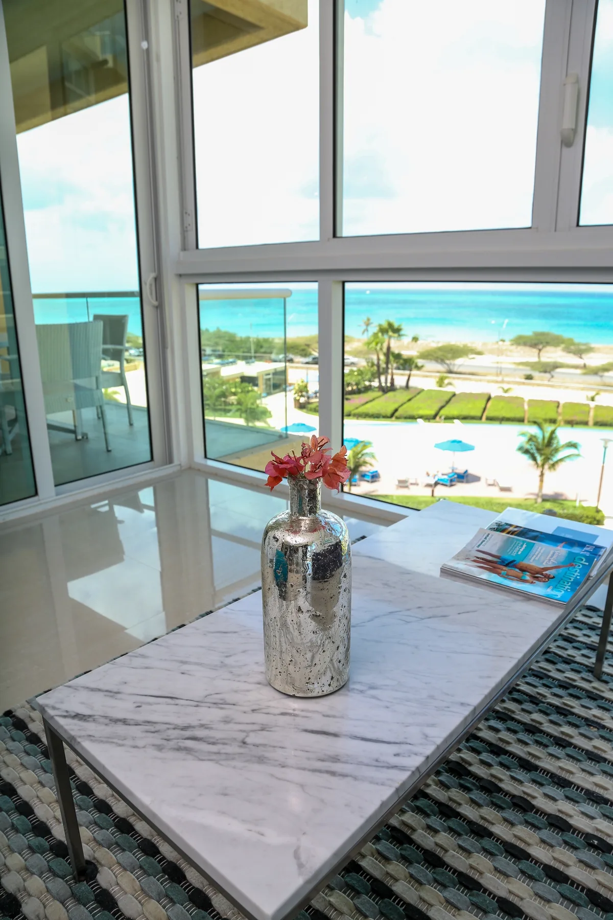 Through your windows, stunning turquoise waters and lush coastal gardens create a breathtaking daily backdrop. The marble-topped table is ready for morning coffee with a view.