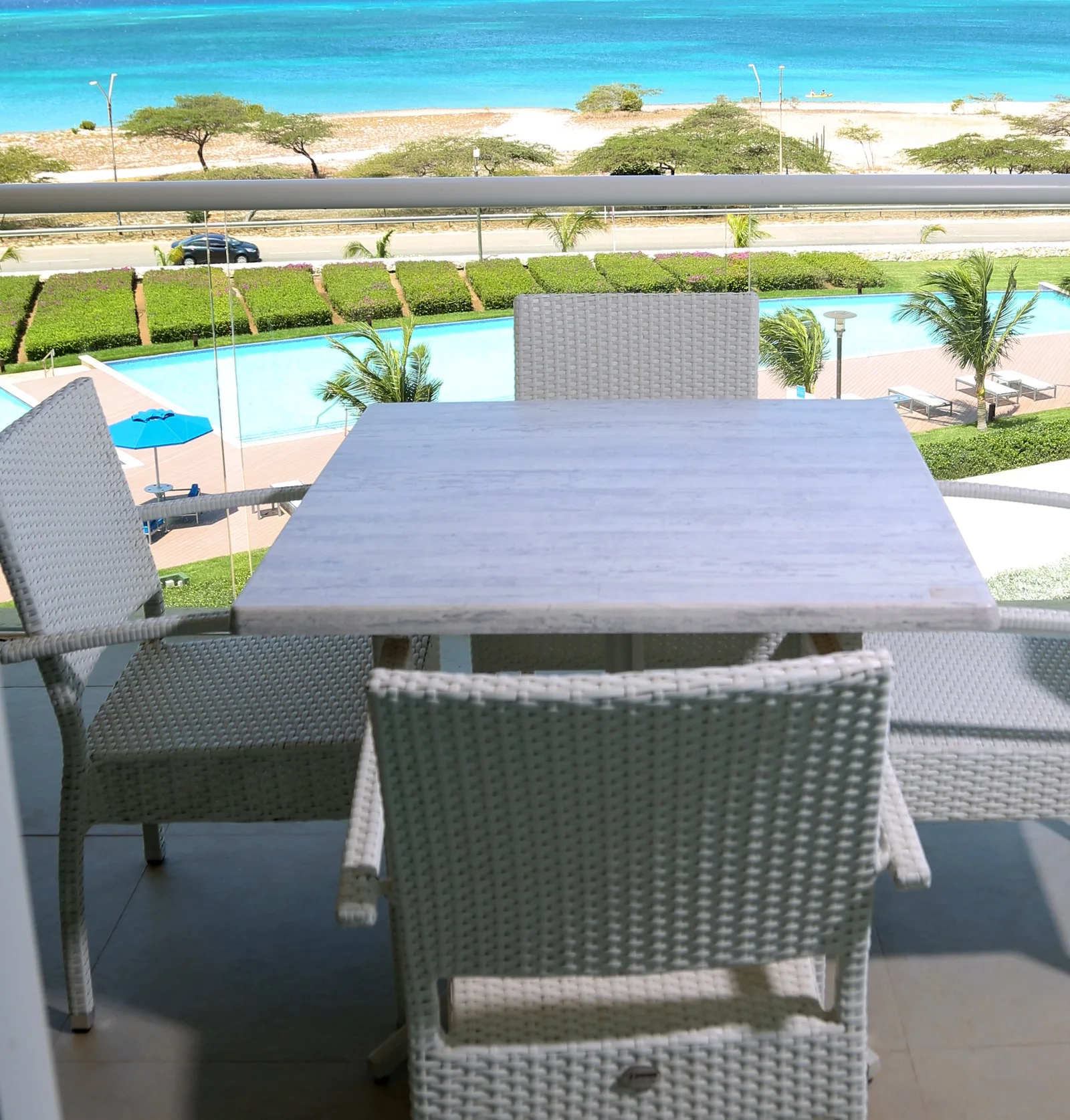 Balcony overlooks a sparkling pool and the turquoise ocean beyond—a beautiful tropical retreat where you can sip morning coffee or unwind at sunset.