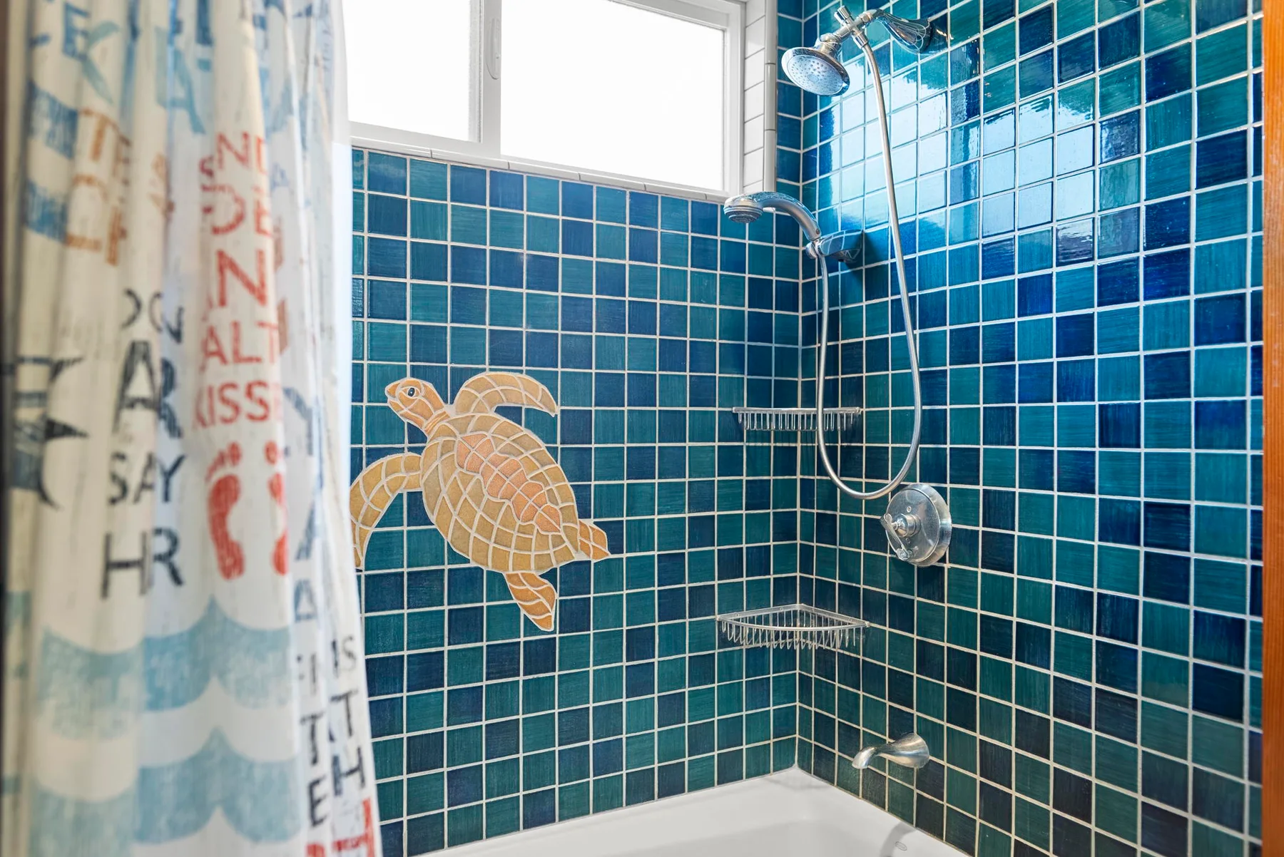 Ducha de baño alicatada con un mosaico de tortuga marina en la pared.