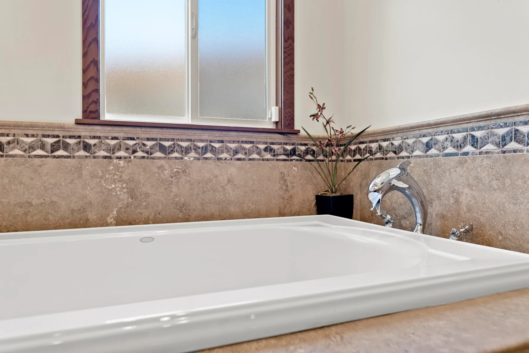 Un baño con una bañera blanca grande bajo una ventana esmerilada.