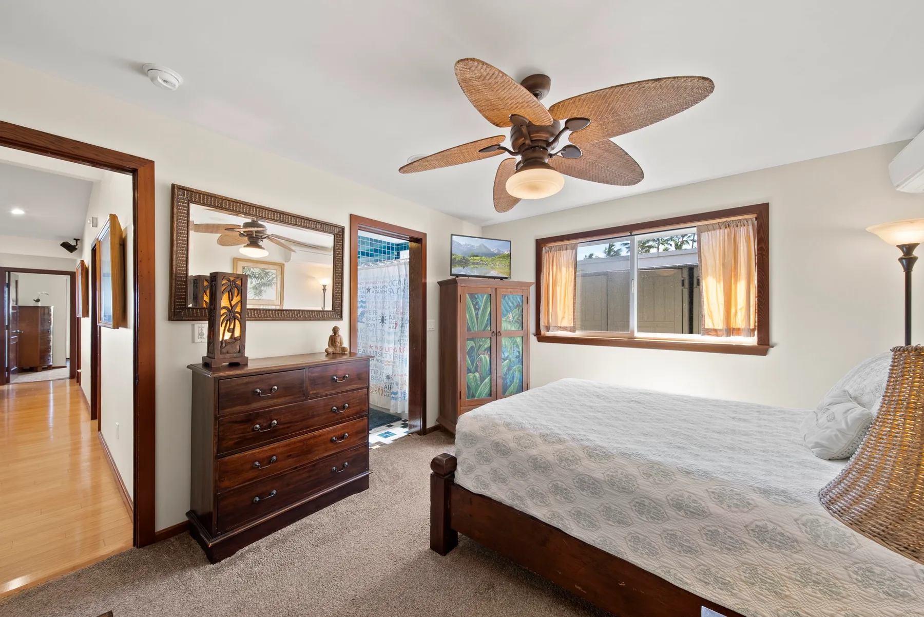 Un dormitorio con una cama grande, una cómoda de madera y un ventilador de techo.