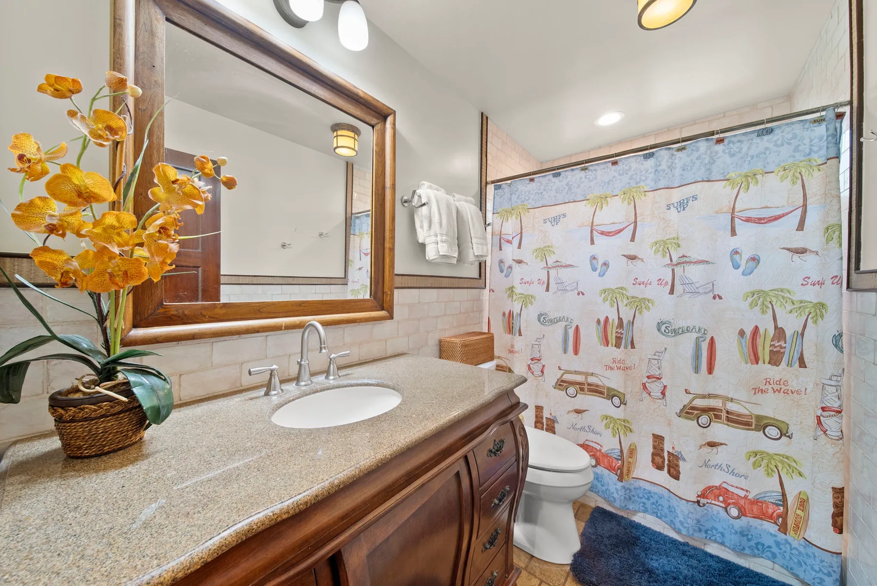 Un baño con lavabo, espejo y una cortina de ducha colorida.