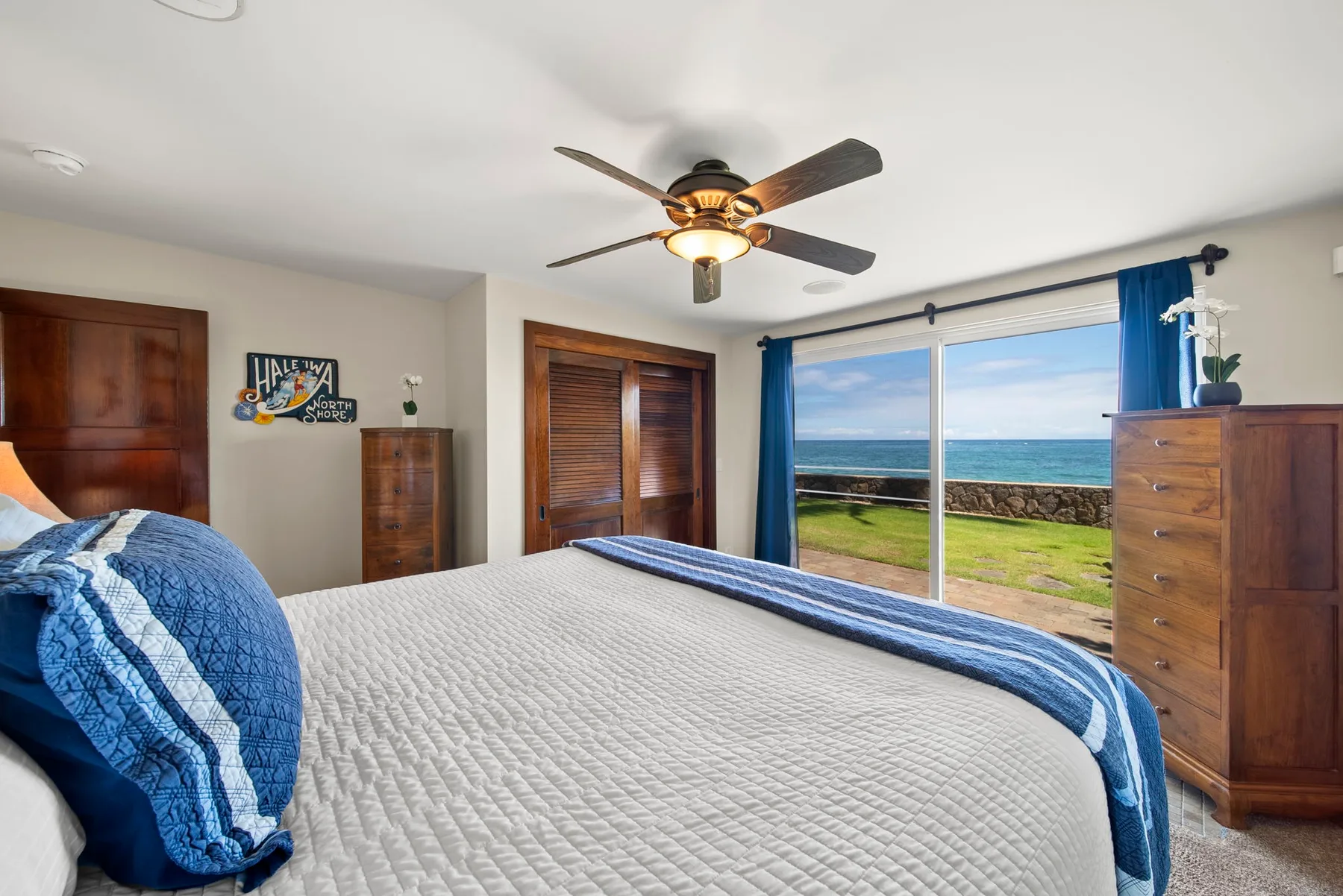 Un dormitorio con una cama frente a grandes ventanas con vista al océano.