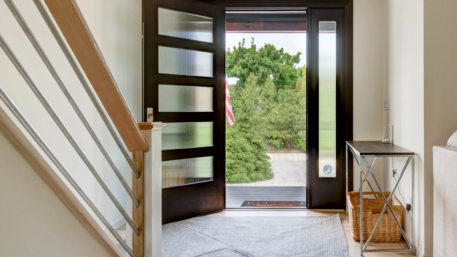 An entryway opens through a dark-framed glass door to greenery outside.