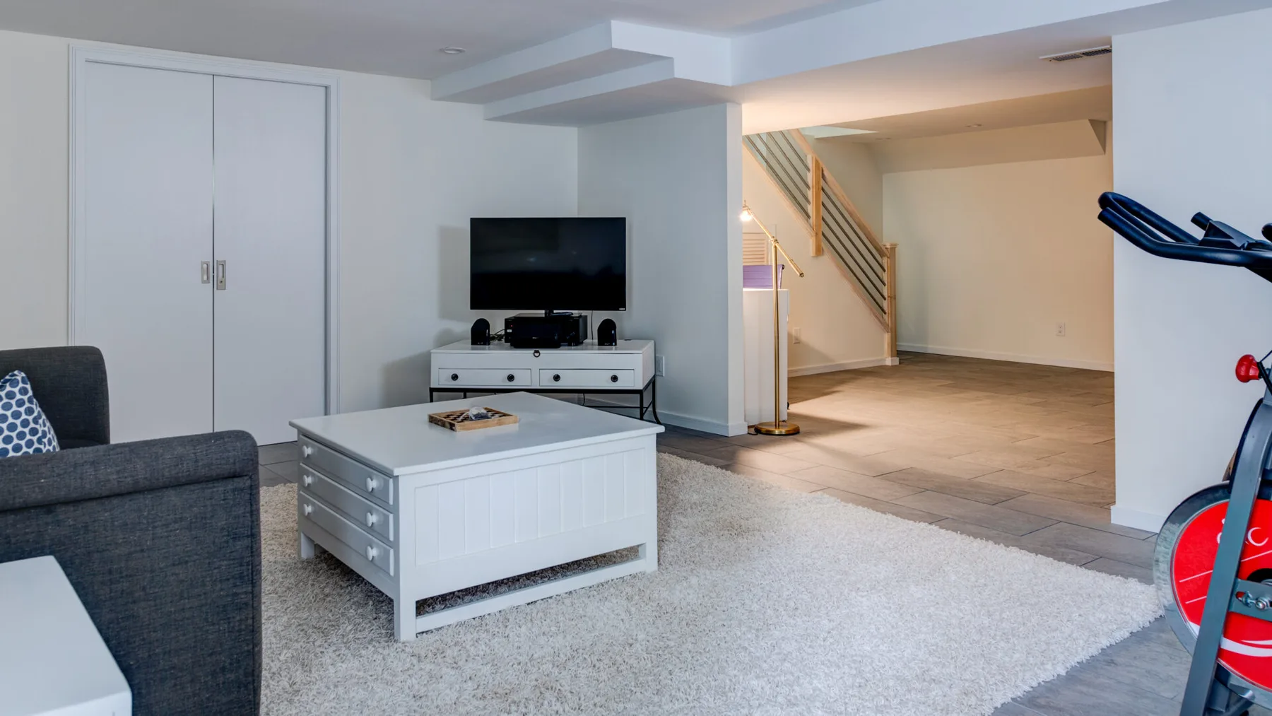 A basement living area with a television and a carpeted seating space.