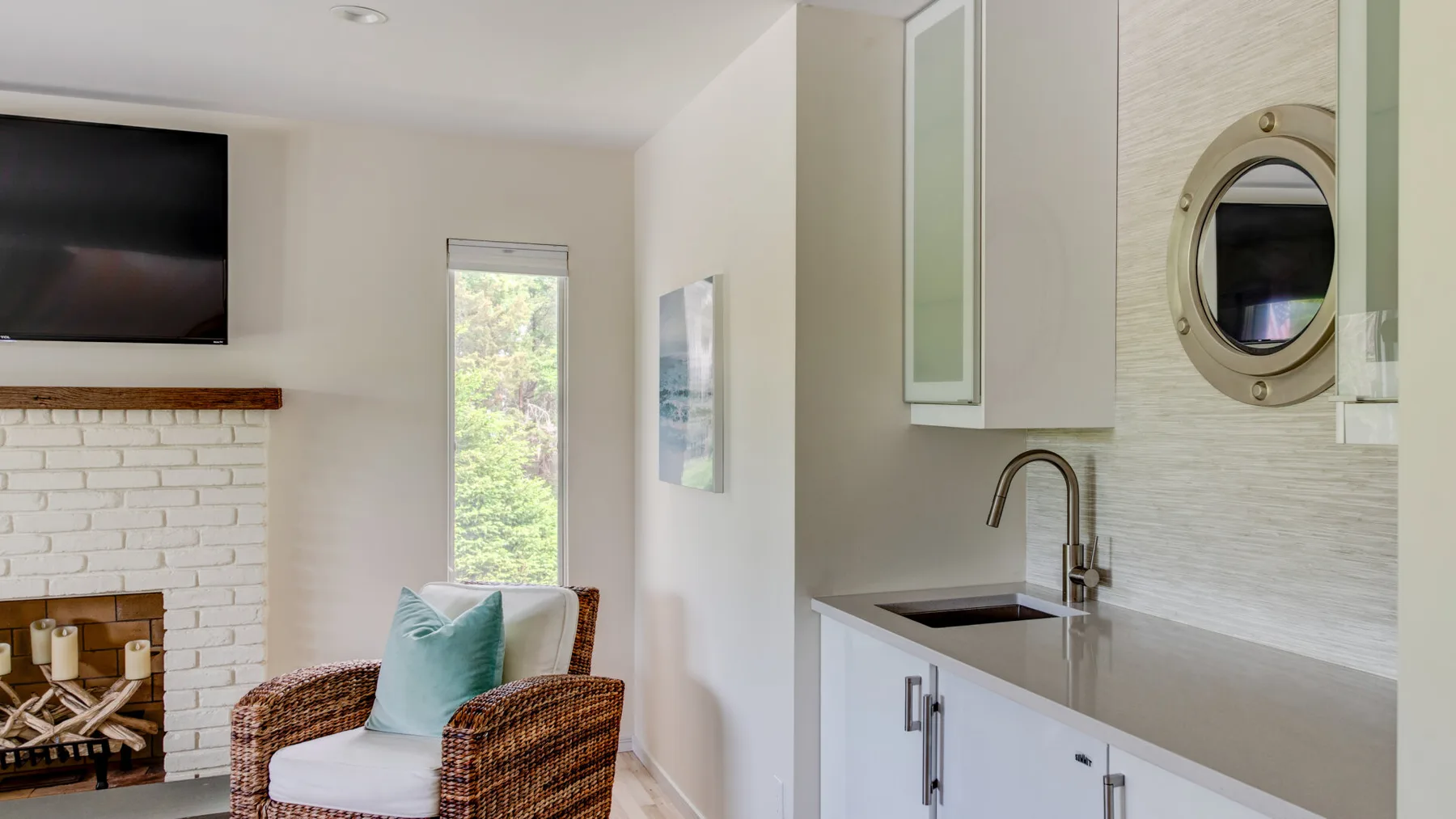 A bright living area with a fireplace, seating, and a compact kitchenette.