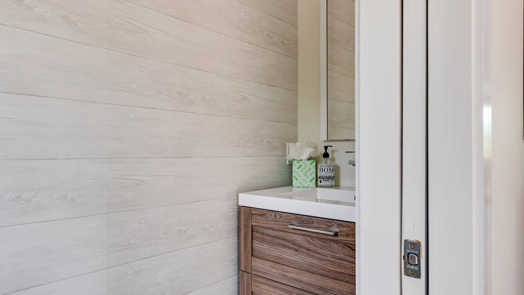 A bathroom vanity with a wood-grain cabinet and toiletries on the counter.