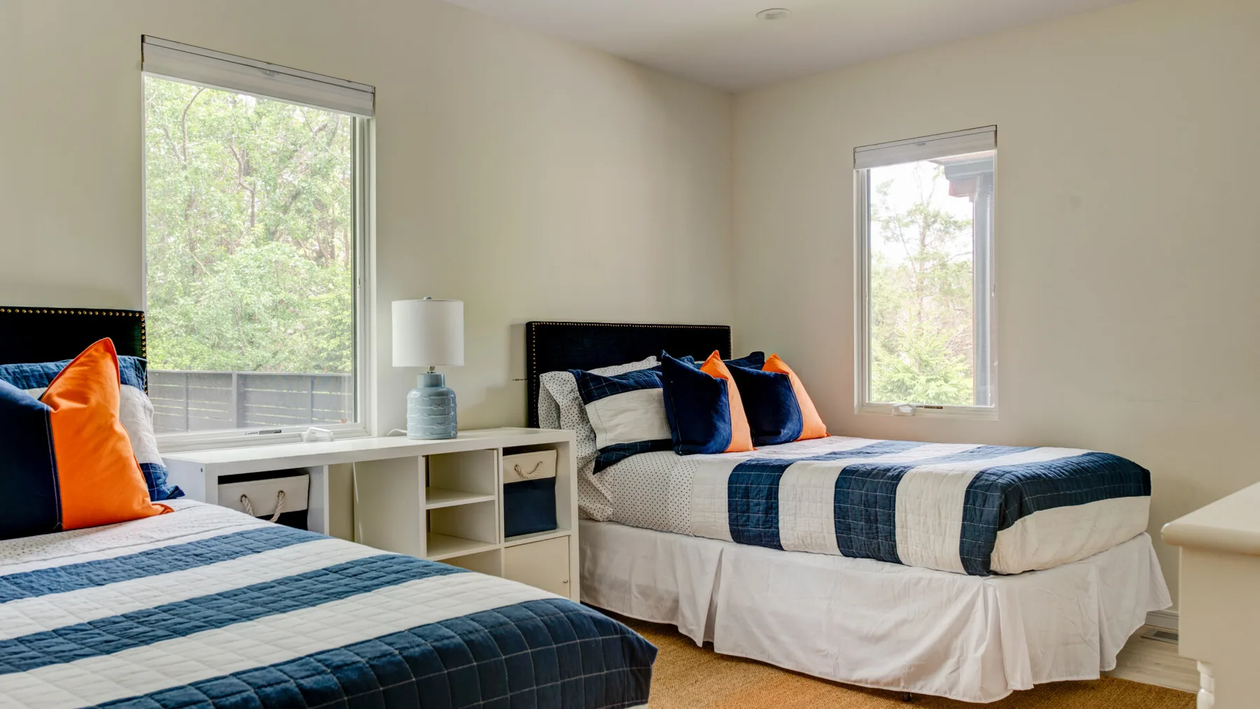 A bedroom with two beds dressed in blue and white bedding.