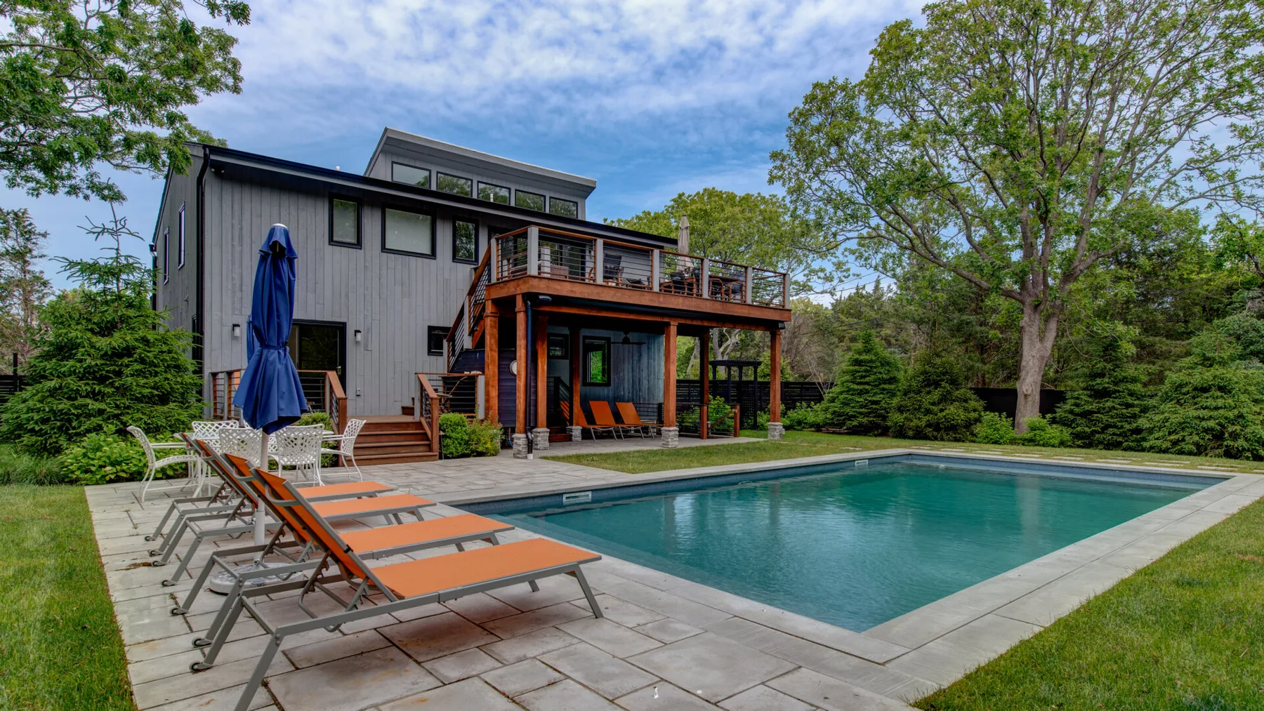 Una casa moderna está junto a una piscina y un patio pavimentado.