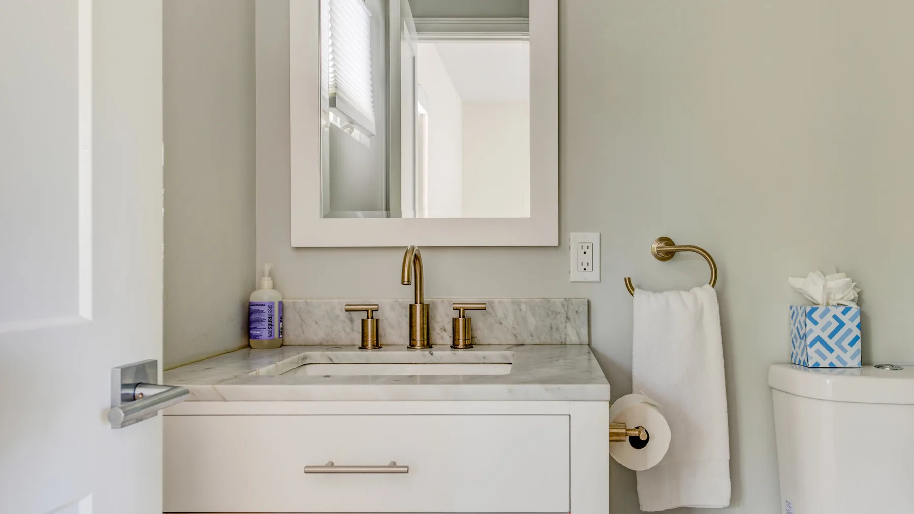 A bathroom vanity with a mirror, towel, and toilet.