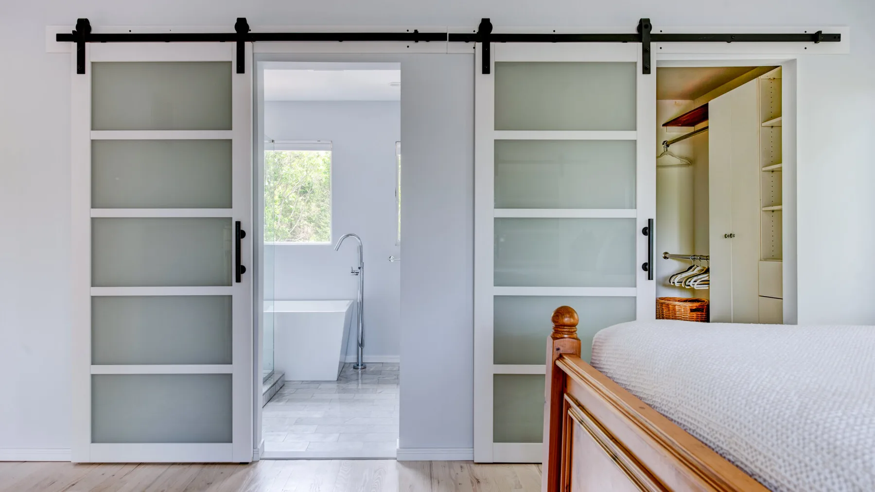 A bedroom with frosted sliding doors opening to a bright bathroom.