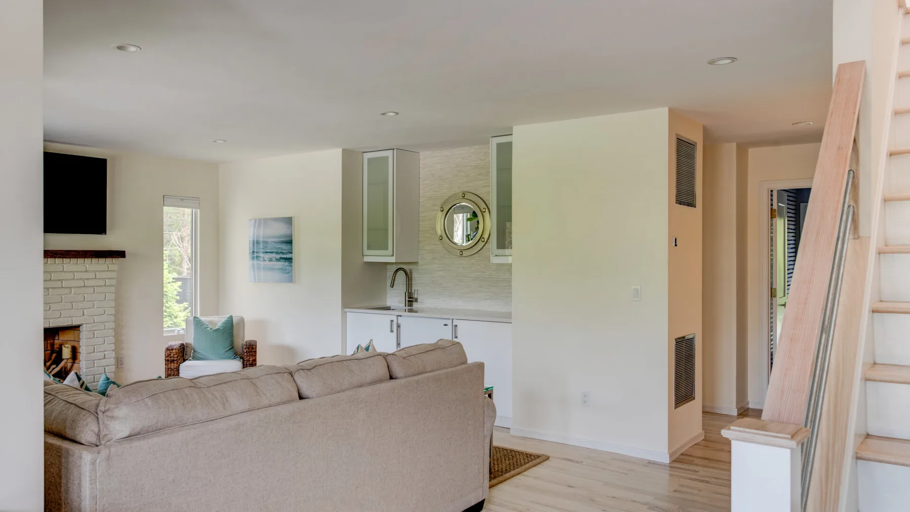 A living room opens onto a compact kitchen, with a sofa facing the fireplace.