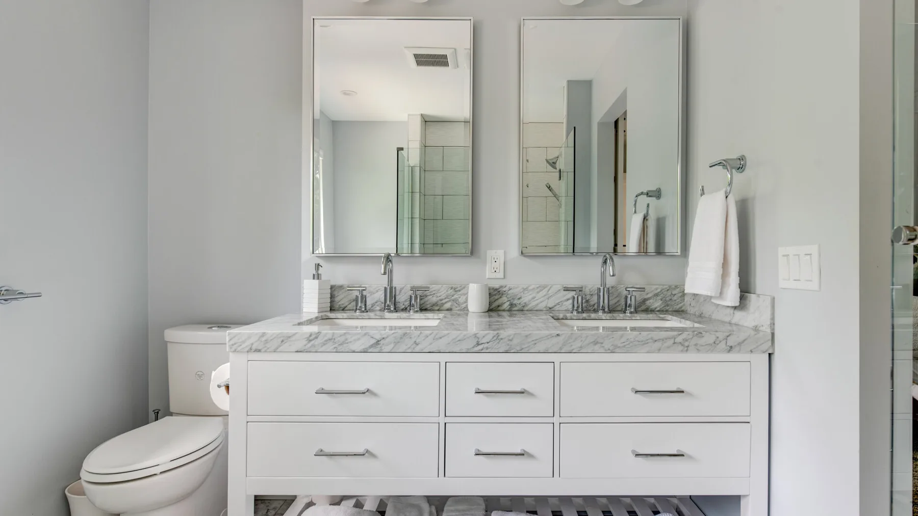 A bright bathroom with a double-sink vanity and a toilet.