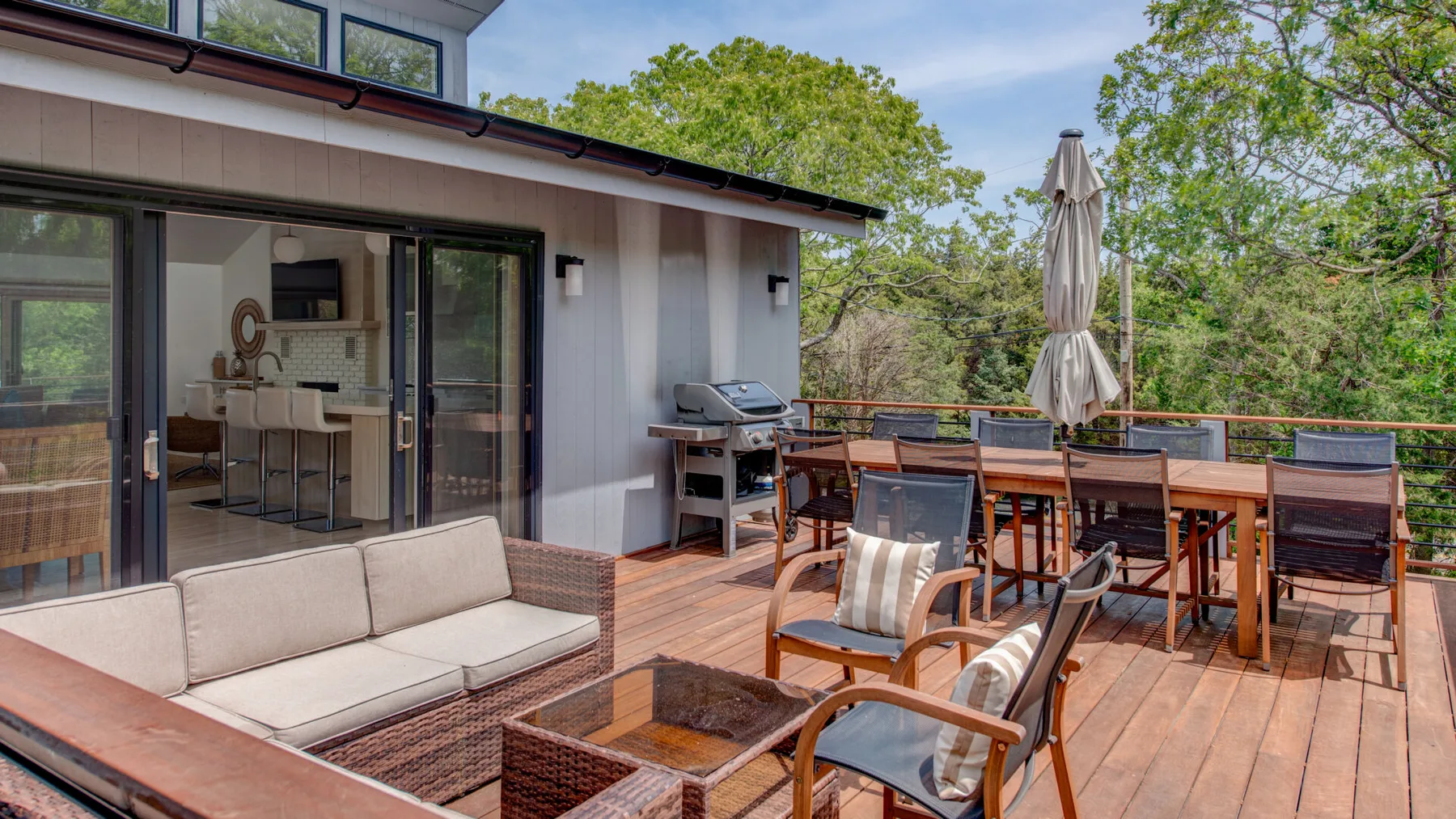 An outdoor deck with dining furniture and a seating area beside the house.