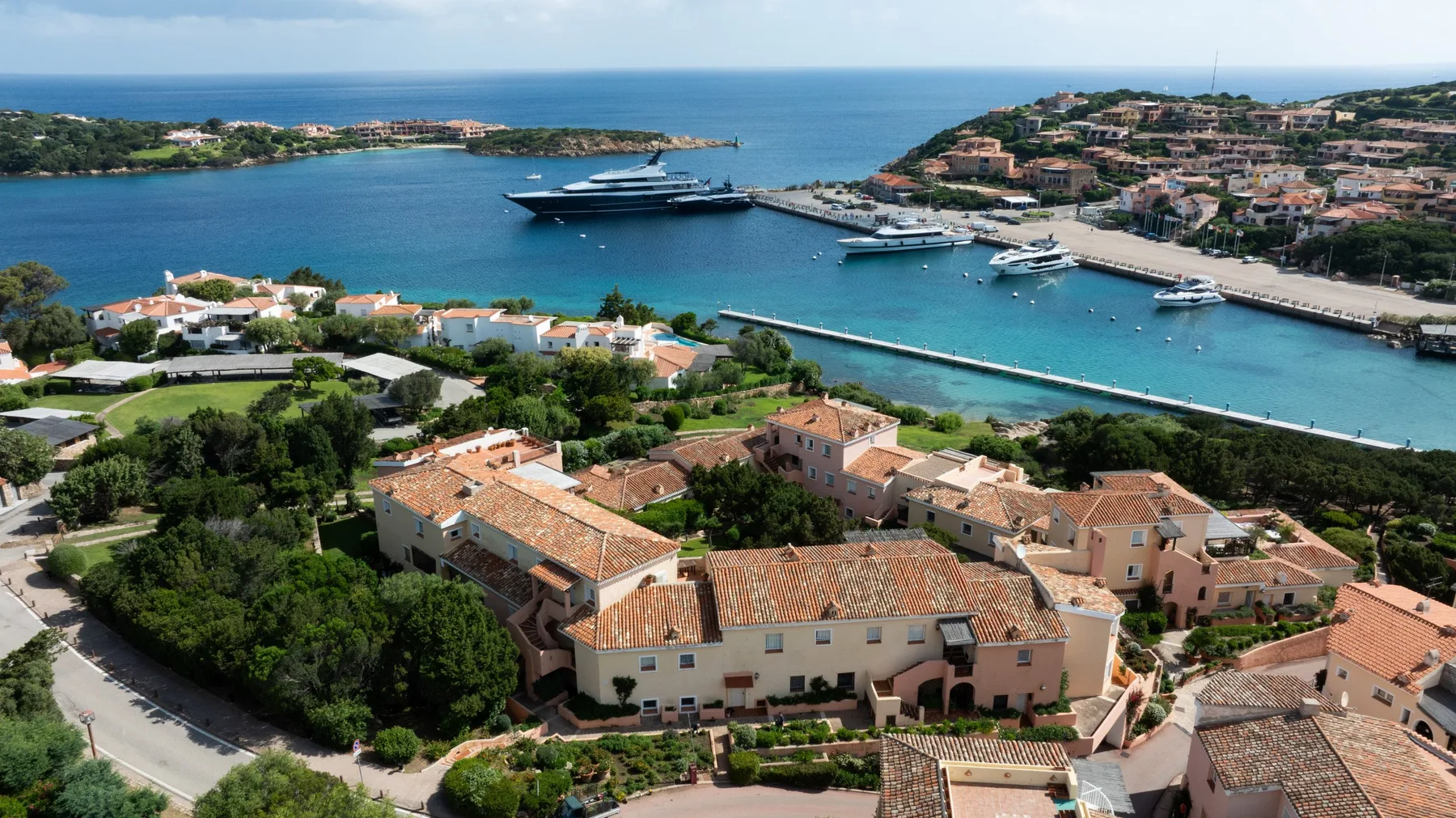 Aerial view of coastal buildings beside a marina and blue water.