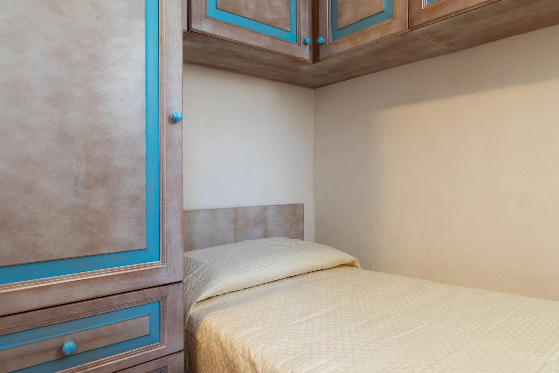 A bedroom with a bed beneath built-in wooden cabinetry.