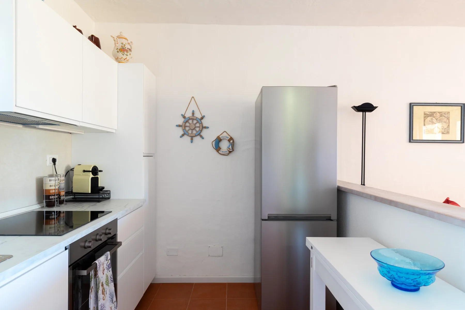A bright kitchen with white cabinetry, a stovetop, and a refrigerator.