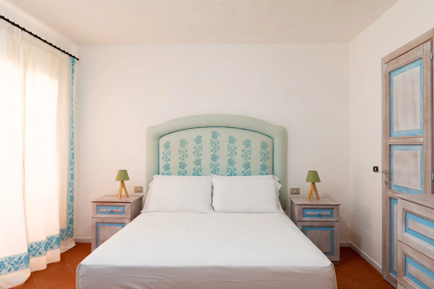 A bedroom with a bed between two bedside tables.