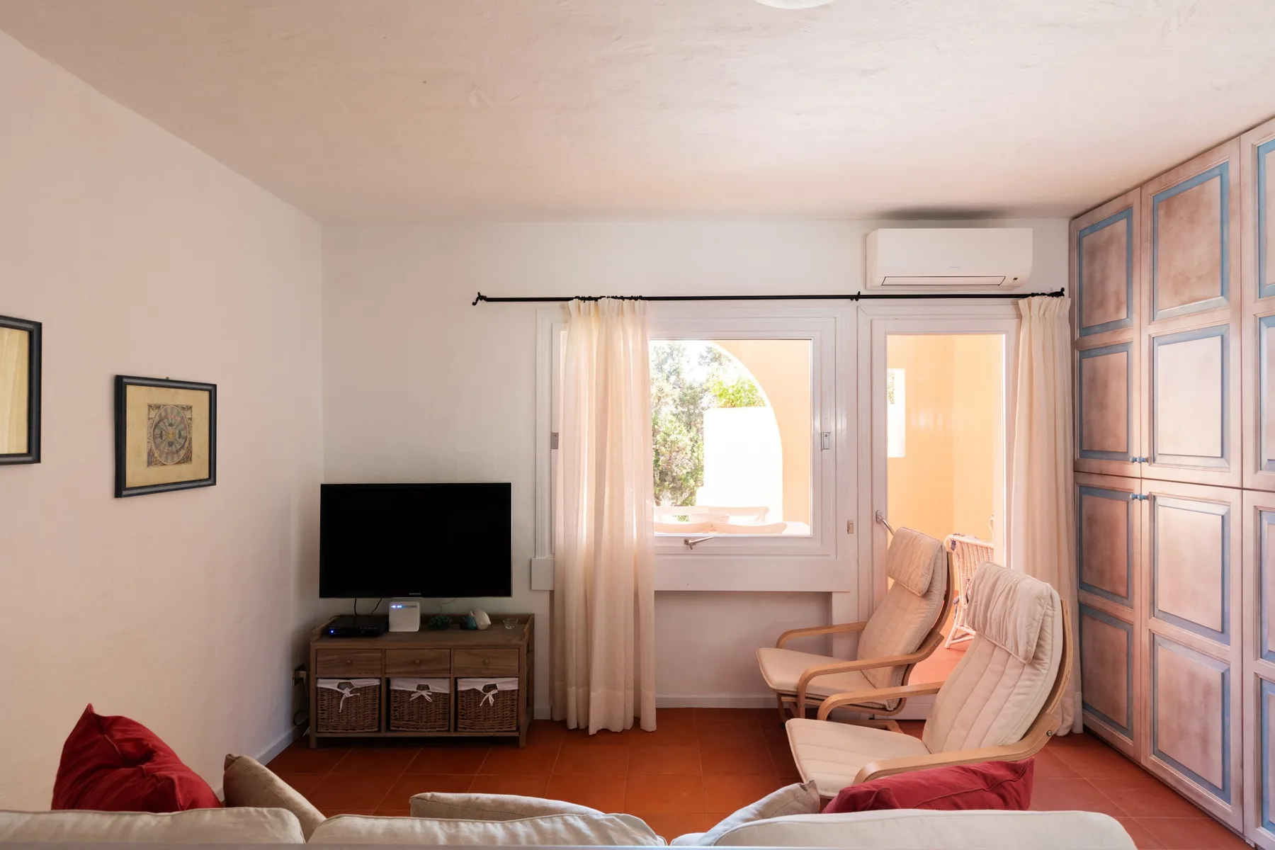A living room with a television, seating, and a window with curtains.