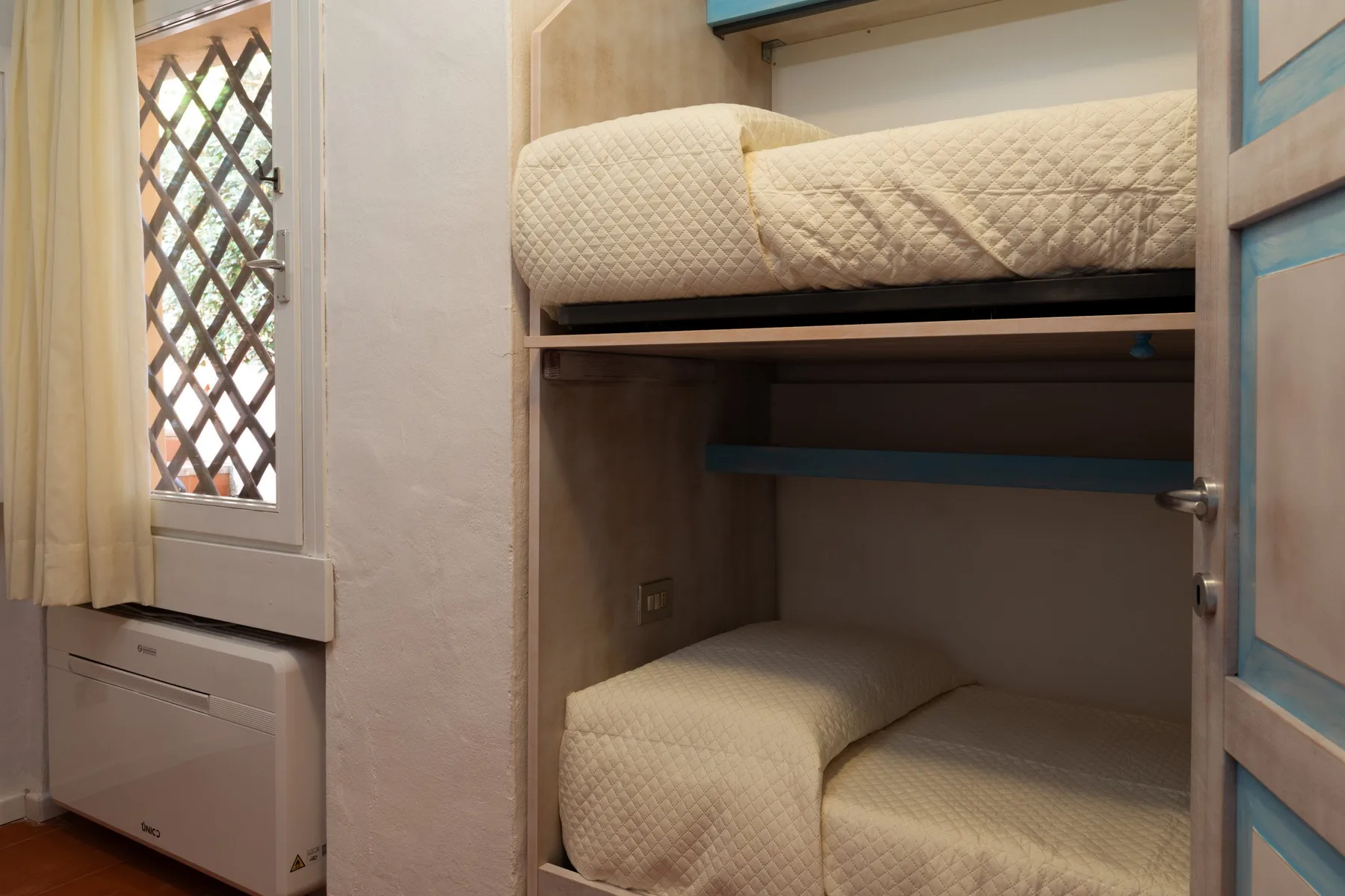 A compact sleeping area with two stacked beds and a curtained window.