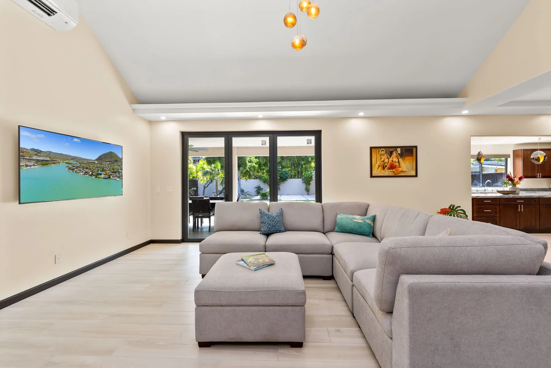 A bright living room with sectional seating and windows overlooking greenery.