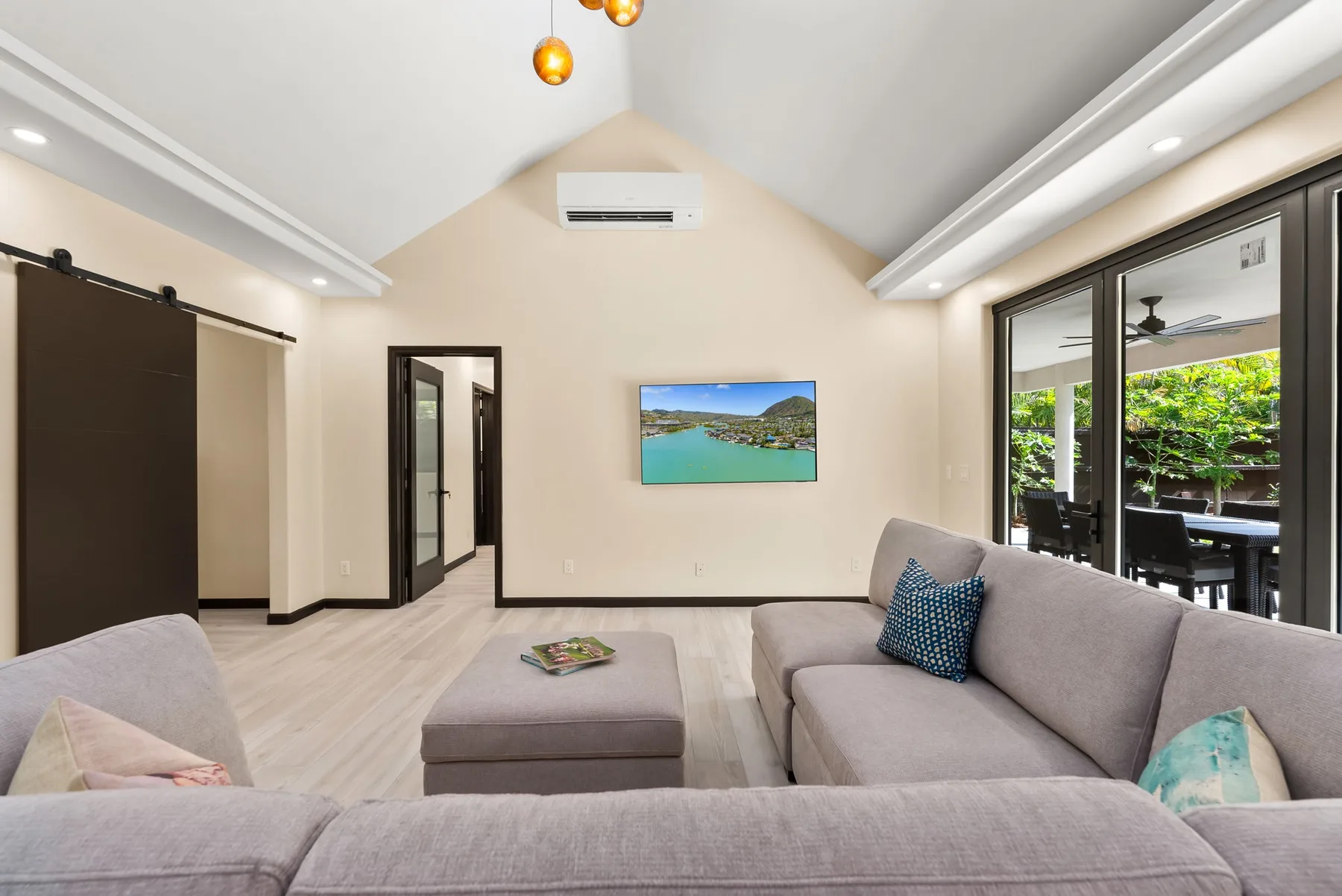 A bright living room with gray seating and large glass doors opening to a garden.