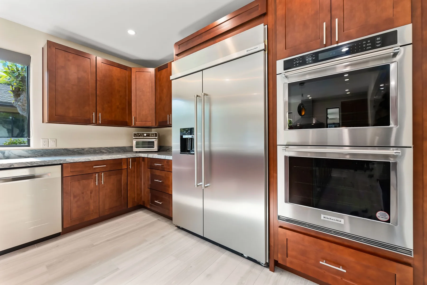 A kitchen with wooden cabinets, a stainless steel refrigerator, and built-in ovens.
