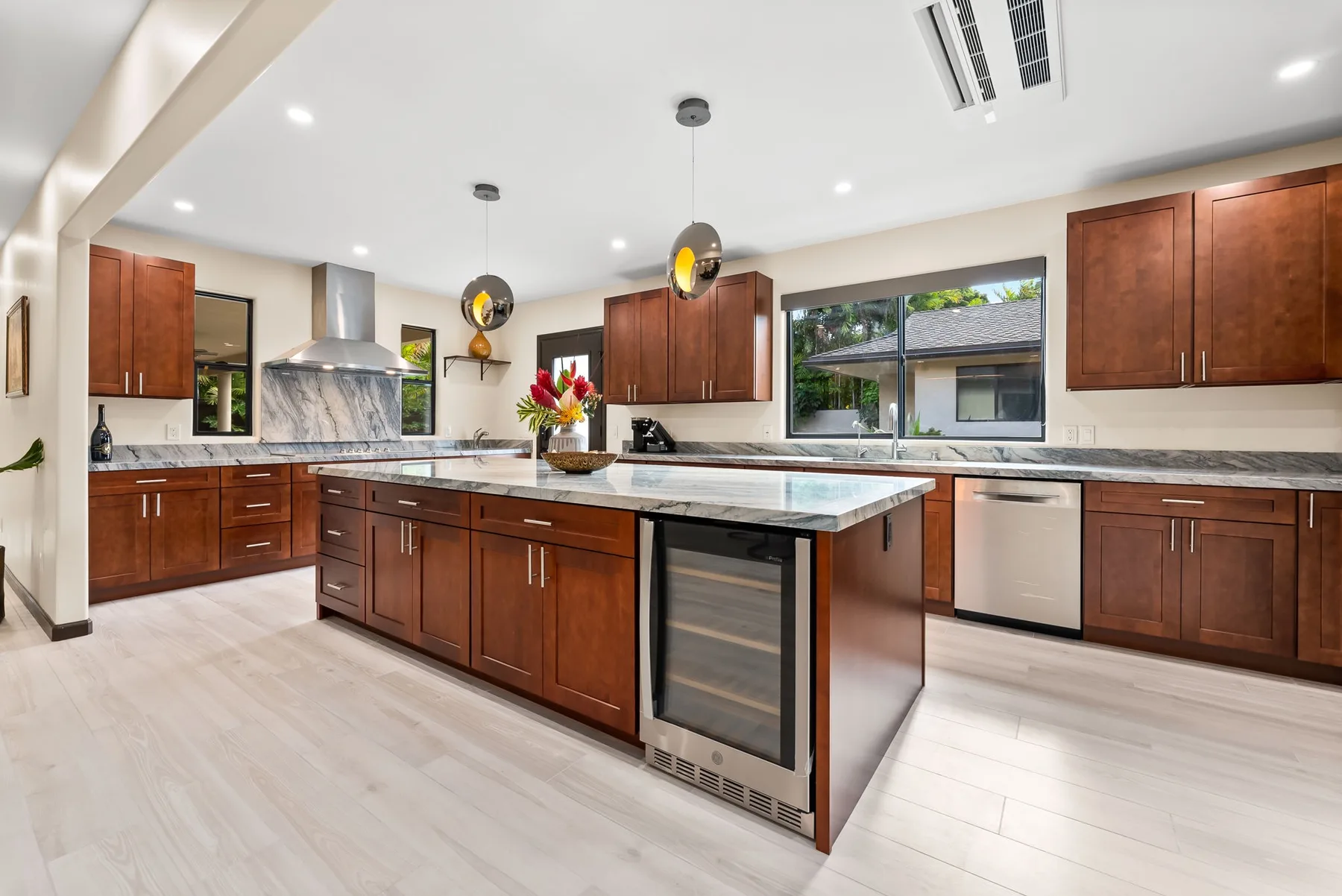 A spacious kitchen with wooden cabinets, stone counters, and a central island.