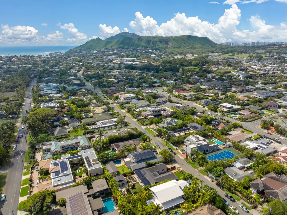 Aerial view of a residential neighborhood with green hills in the distance.