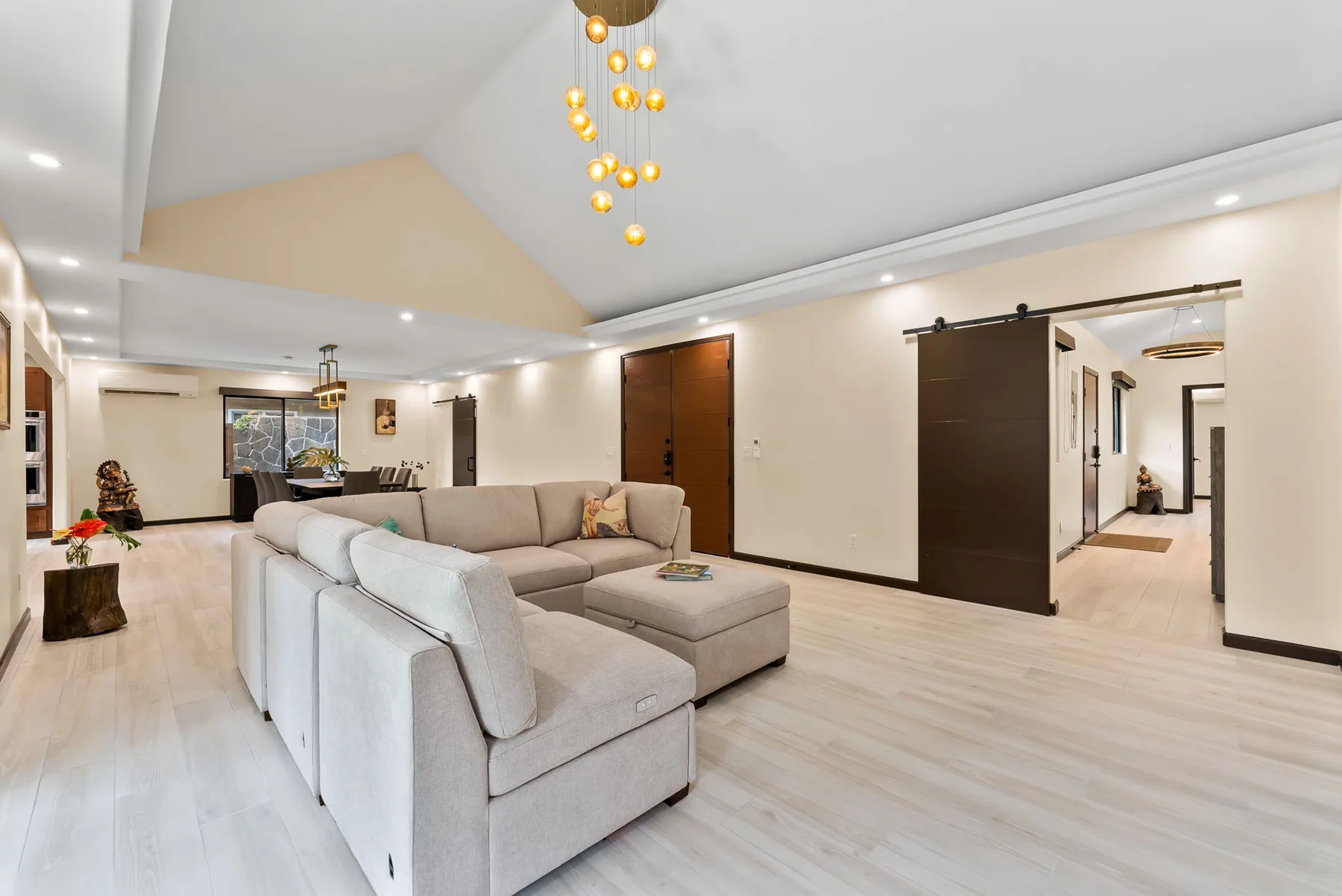 A bright living room with a sectional seating area and a hanging light fixture.