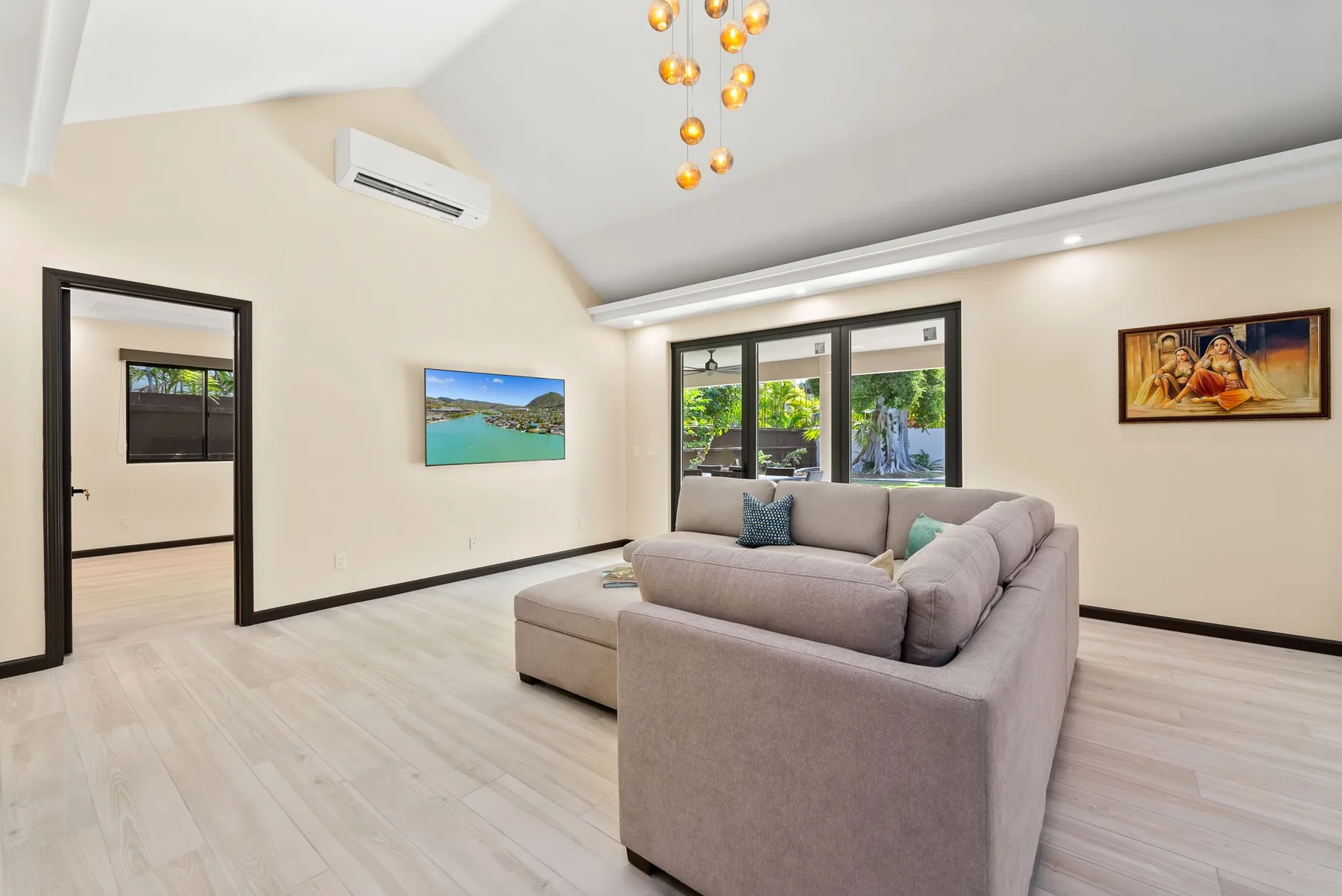 Una sala luminosa con un sofá seccional frente a grandes ventanas.