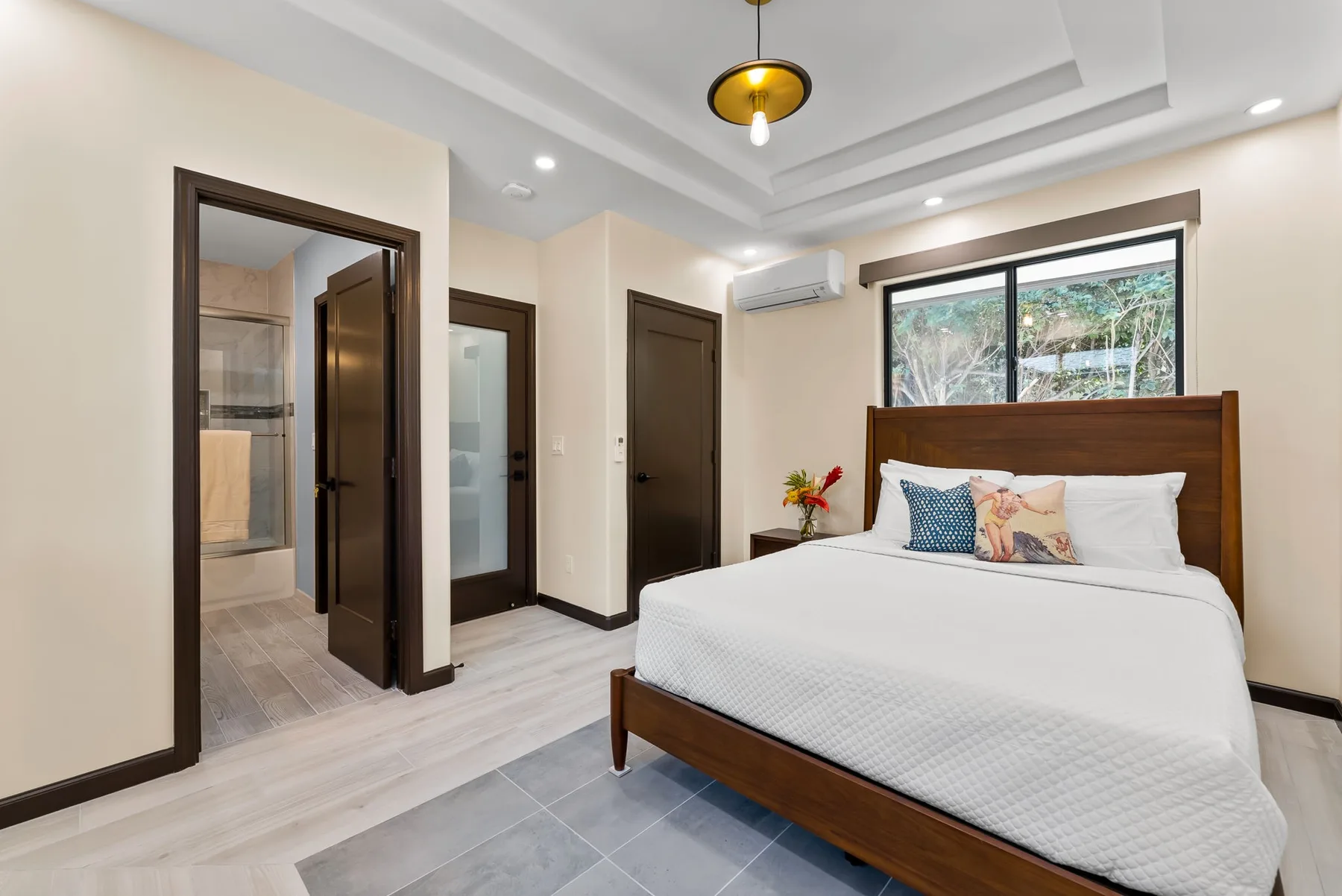 A bedroom with a bed, a window, and an open doorway.