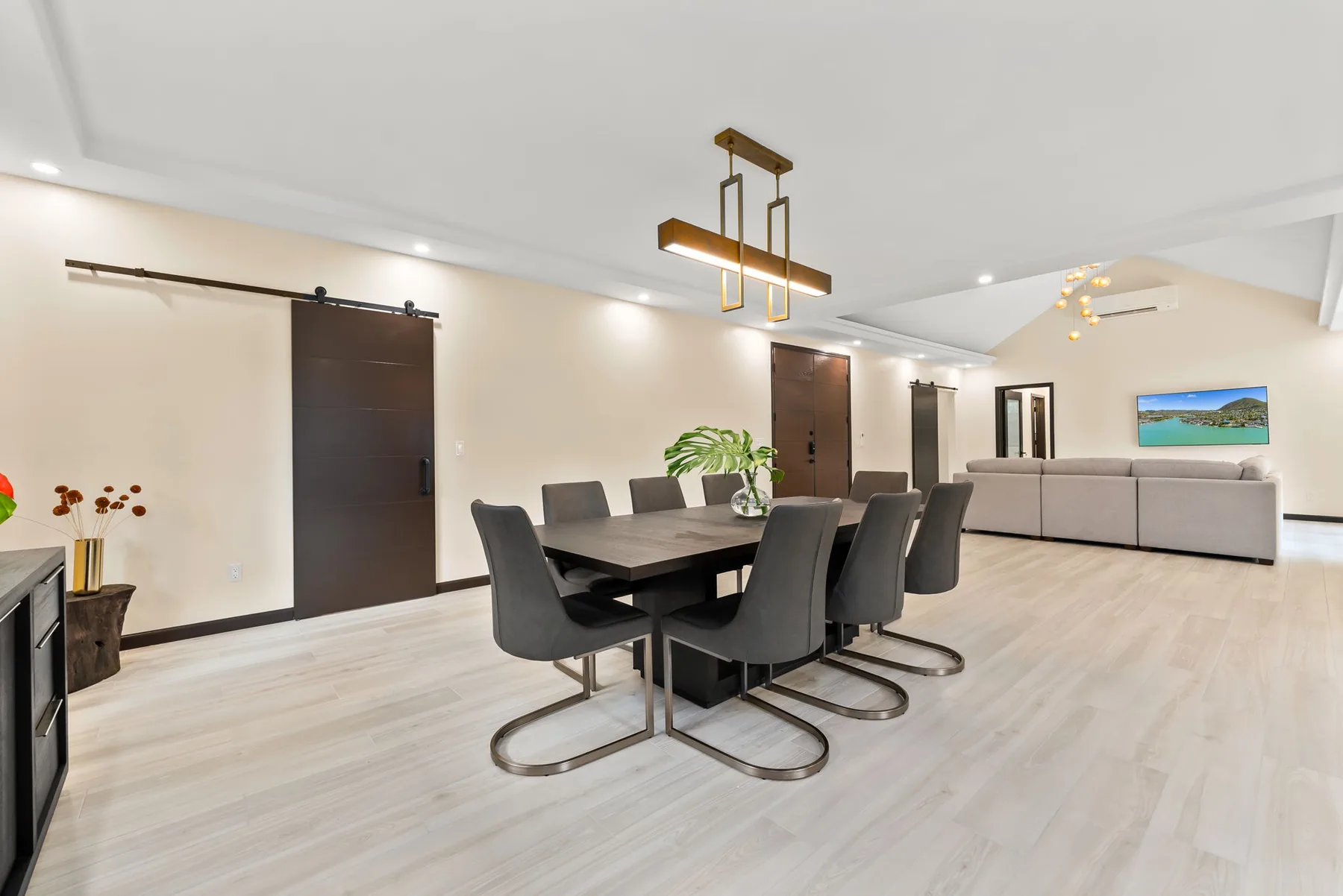 A bright dining and living area with a dark dining table and seating.