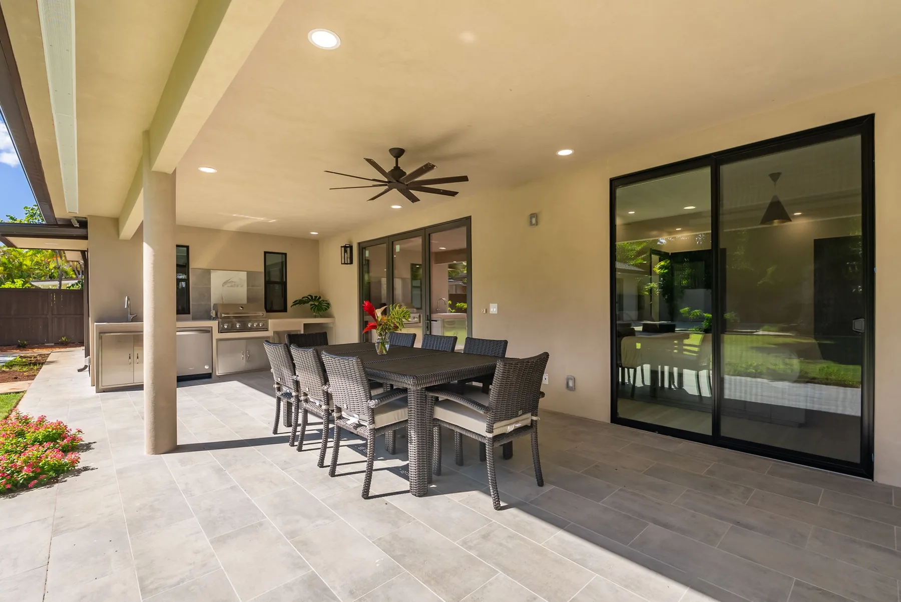 A covered patio with a dining table and outdoor seating beside large glass doors.
